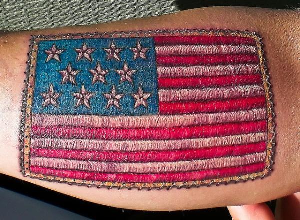 The American Flag Tattoo on the lower font arm brings the ornate look on a man