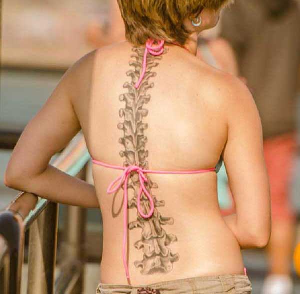 Spine tattoo on the back makes a girl look enchanting