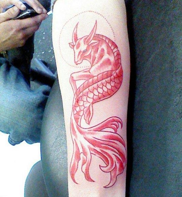 This pink ink design of the Capricorn tattoo front lower arm matches the skin color to make a man look admirable 