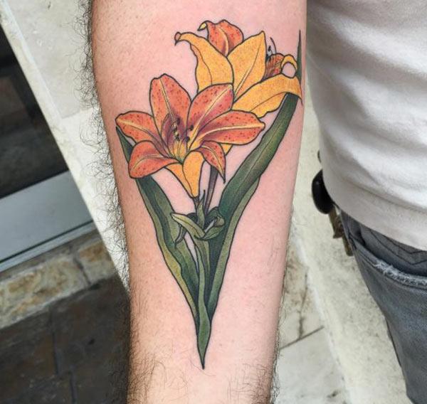 Lily tattoo with an orange and yellow ink design on the lower arm shows their foxy look 