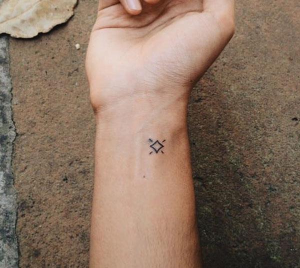Tiny tattoo on the wrist with a black ink design makes a girl appear charming