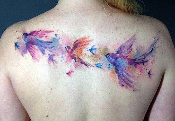 Watercolor tattoo with birds across the back brings the appealing look