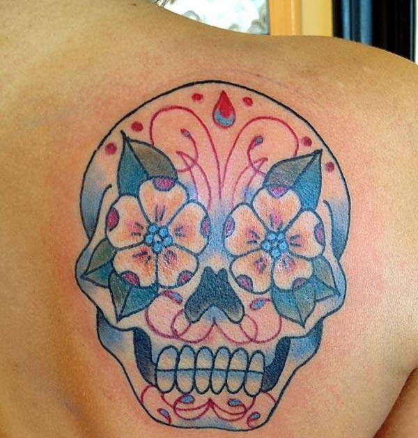 The sugar skull tattoo on right part of female back at the top side