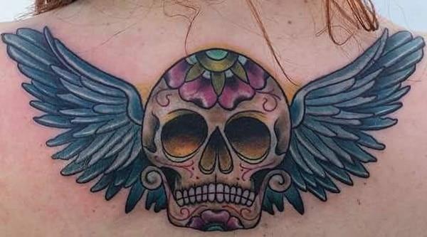 The best sugar skull tattoo with wings on top of the back of female