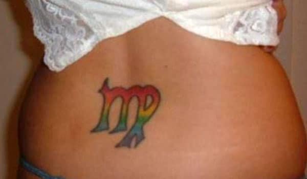 Virgo tattoo at the lower back with an orange, yellow and blue ink design makes a girl look attractive
