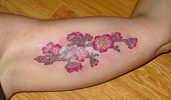 Bicep tattoo with a pink flower ink design make a man look cute