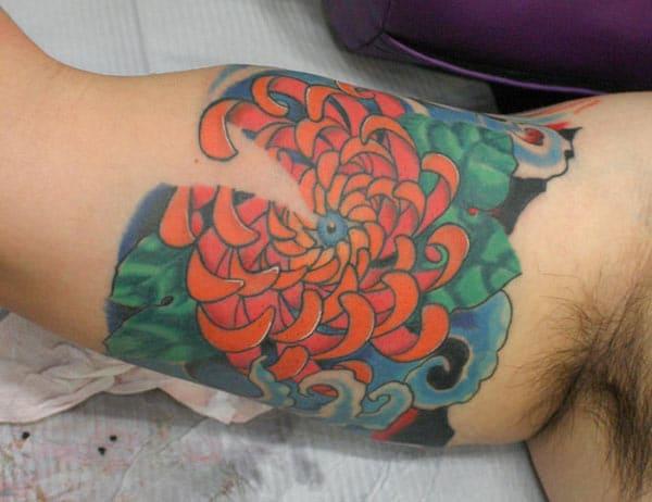 The Bicep Tattoo with an orange, blue and green ink design make a man look admirable
