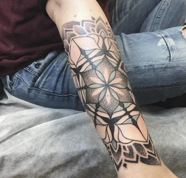 Forearm Tattoo with a green and black flower ink design makes a girl look alluring