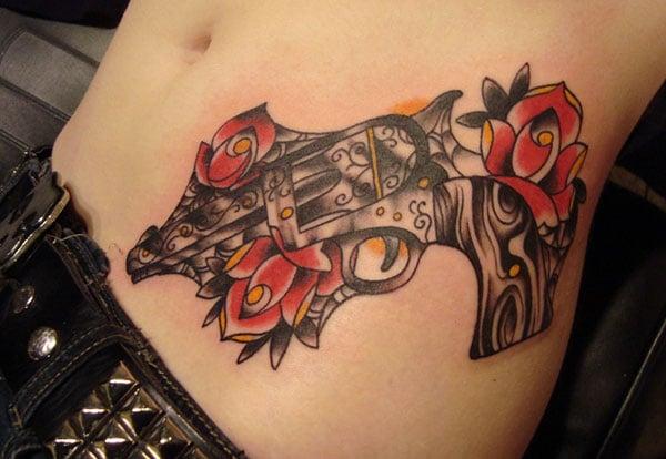 Gun Tattoo on above the hips with a black ink design brings the captivating look