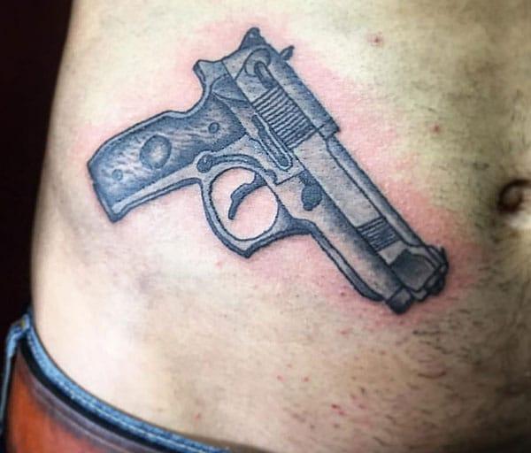 Gun Tattoo on the side belly make a man look cool