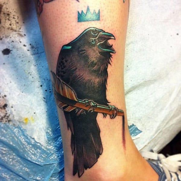The dark design ink of the Raven tattoo on the foot matches the skin color give a man a dapper look