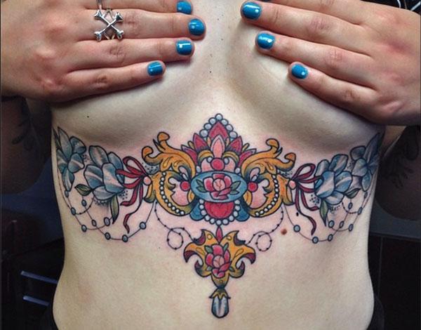 Sternum tattoo for Women with a blue and pink flower ink design makes them appear comely