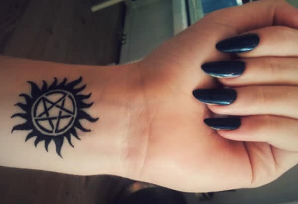 Supernatural tattoo on the wrist with a black ink design makes a girl appear charming