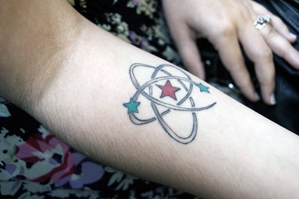 Atomic Tattoo on the lower arm with red and blue stars makes a girl appear charming