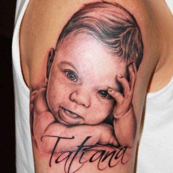 Baby tattoo on the shoulder with dark ink design makes a man look cute