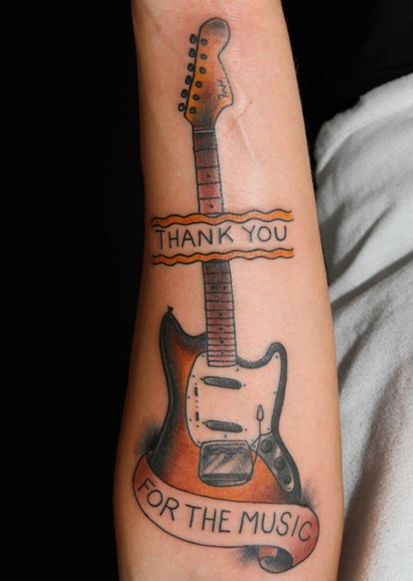Guitar Tattoo with a brown ink design on the lower arm shows their foxy look