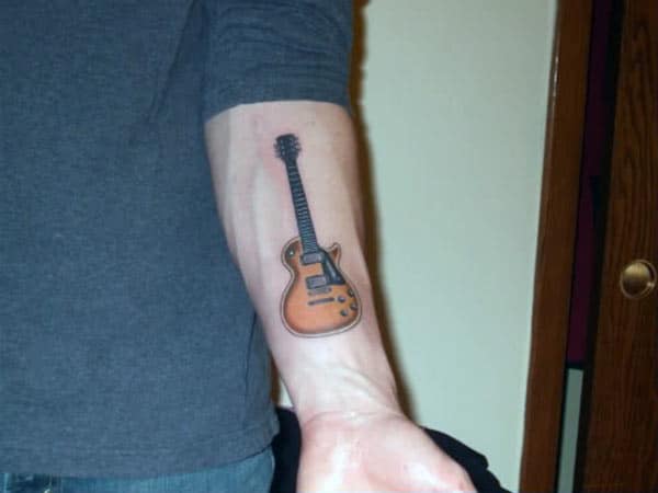 Guitar Tattoo with a brown and black ink design on the lower arm shows their foxy look