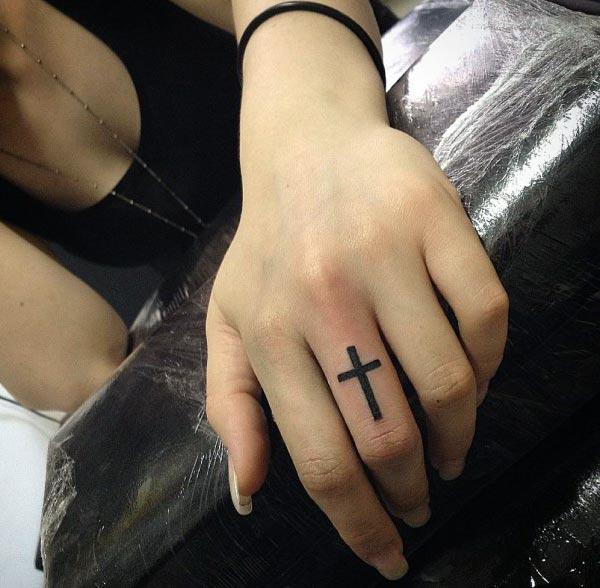 Girl’s middle finger designed with a cross tattoo appears cool