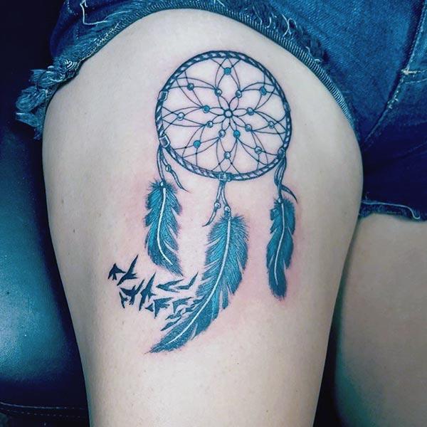 Dreamcatcher tattoo for the upper thigh brings their feminist look.