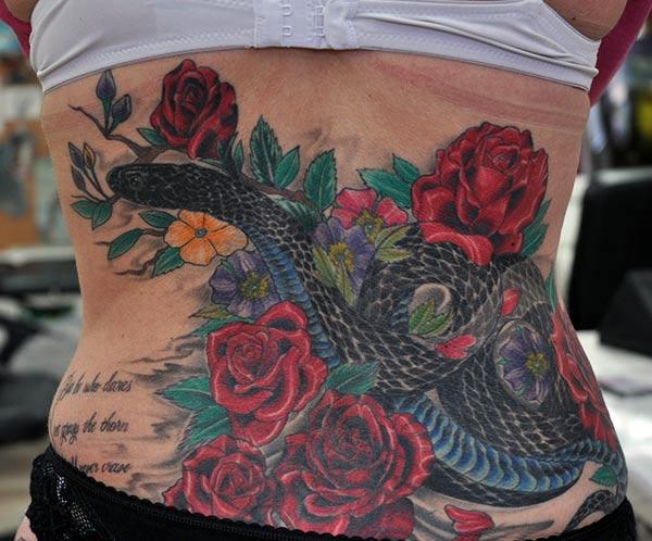 Snake tattoo designed with black and blue ink at the lower back make girls look attractive.