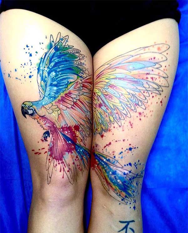 Vibrant looking magical parrot watercolor thighs tattoo idea for Trendy Women