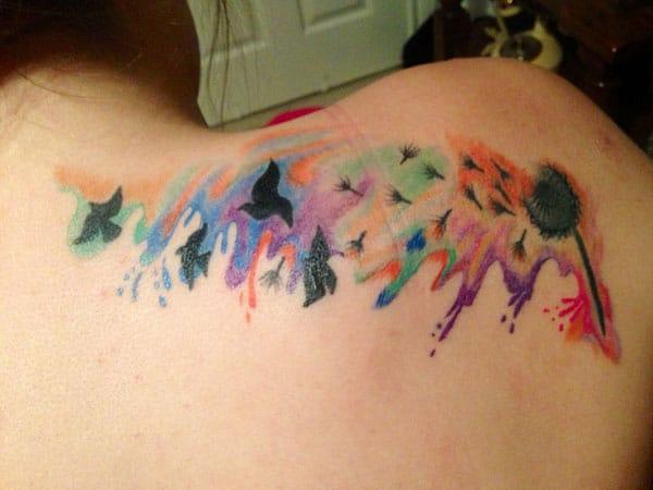 Ladies watercolor tattoo ideas on back shoulder of bird from dandelion flowers