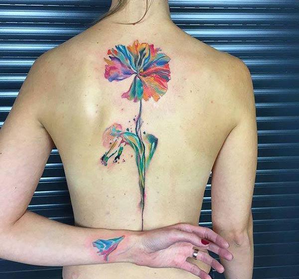 Girl’s Multi bright colored large flower with stalk tattoo on back 