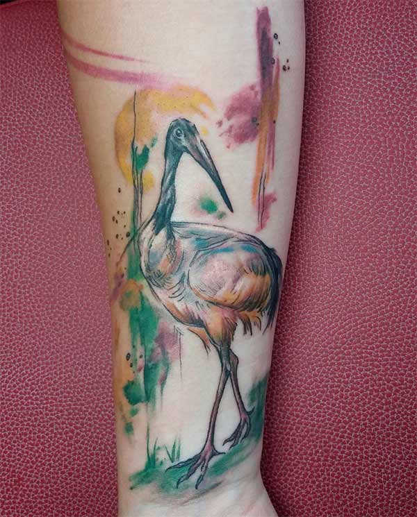 Amazing stork in field at sunset watercolor tattoo on forearm for female art lovers