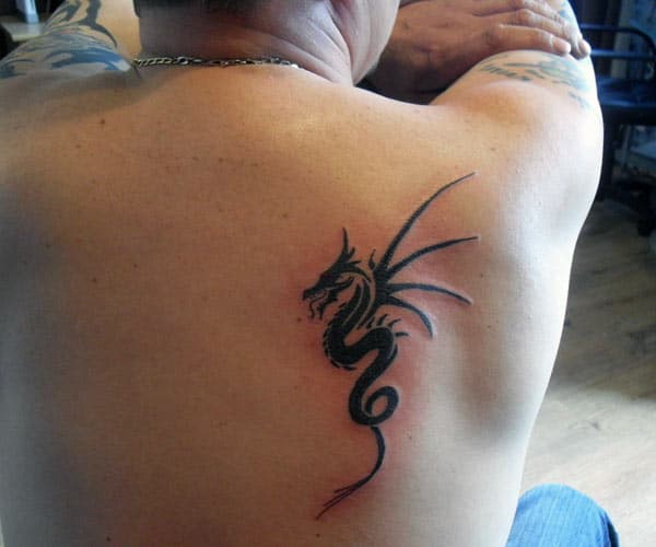Small black tribal dragon tattoo on back for Guys