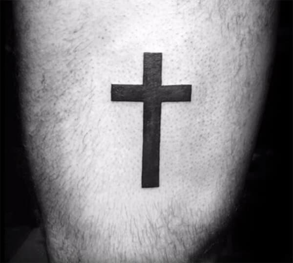 Broad black cross tattoo design on thigh for men