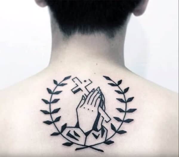 Impressive cross in hand enclosed in leaves tattoo design on back for boys and men