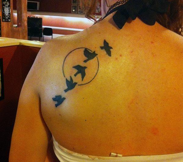 tattoo has birds flying in front of sun or moon 
