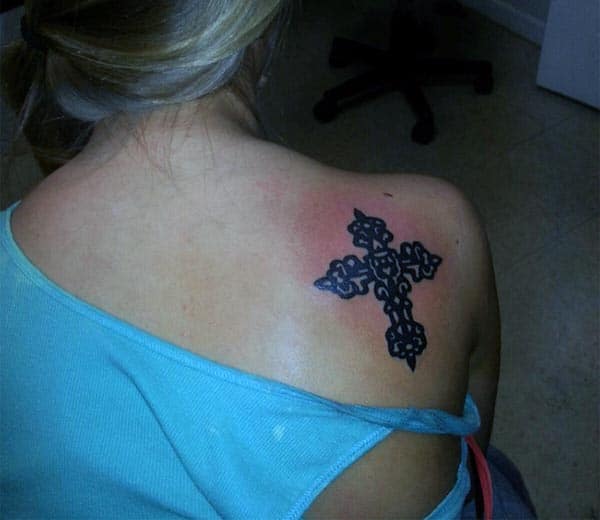 A bold cross tattoo design on back shoulder for ladies