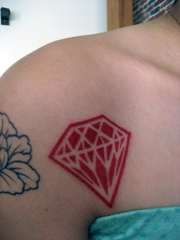 A cute red diamond tattoo on front shoulder for Women