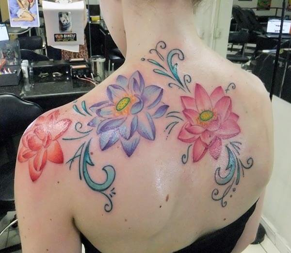 A multi-hued lotus tattoo design on back for women